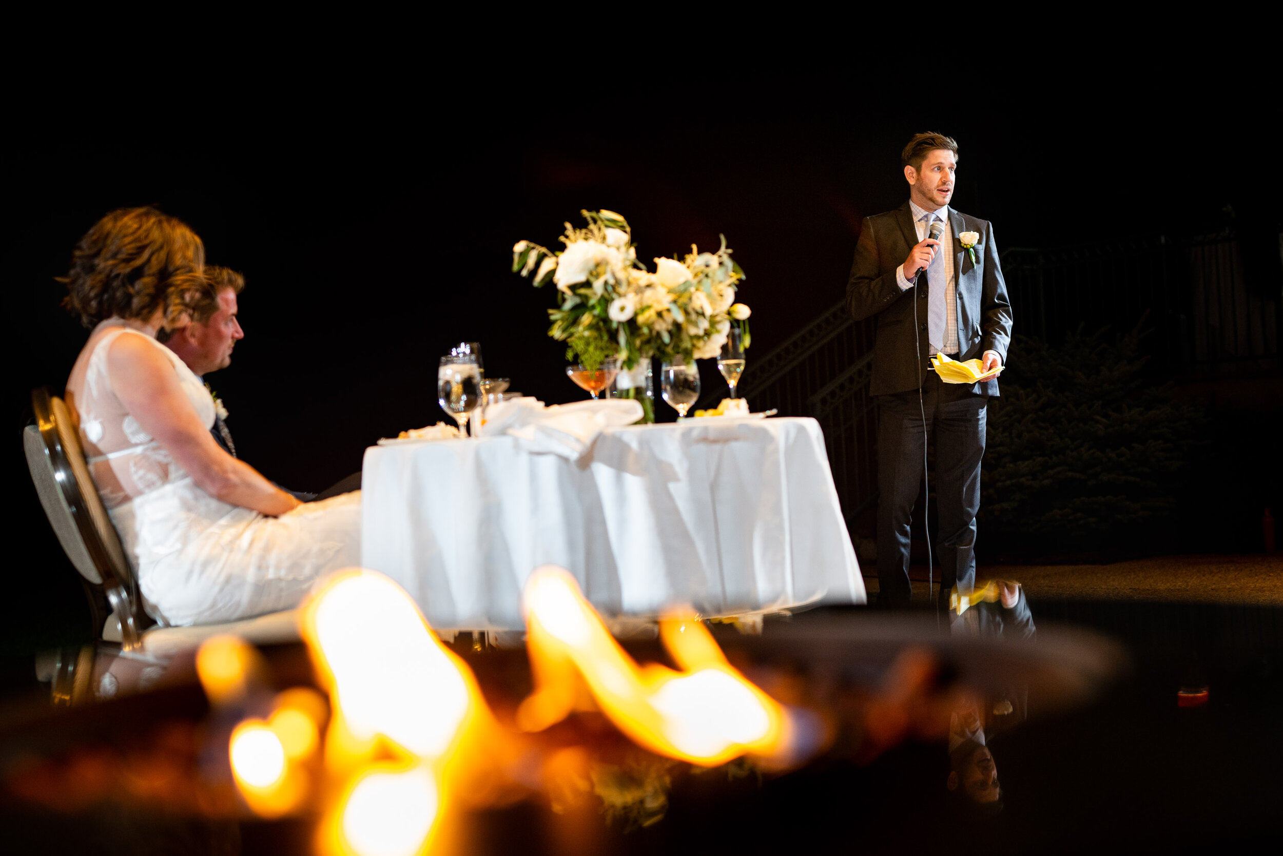 Bride and groom listen to speeches by family and friends during their wedding reception at the Garden of the Gods Club and resort by the reflection pond, wedding photos, wedding photography, wedding photographer, wedding inspiration, wedding photo inspiration, wedding portraits, wedding ceremony, wedding reception, mountain wedding, Garden of the Gods wedding, Garden of the Gods Club & Resort wedding, Garden of the Gods Club & Resort wedding photos, Garden of the Gods Club & Resort wedding photography, Garden of the Gods Club & Resort wedding photographer, Garden of the Gods Club & Resort wedding inspiration, Garden of the Gods Club & Resort wedding venue, Colorado Springs wedding, Colorado Springs wedding photos,  Colorado Springs wedding photography, Colorado Springs wedding photographer, Colorado wedding, Colorado wedding photos, Colorado wedding photography, Colorado wedding photographer, Colorado mountain wedding, Colorado wedding inspiration