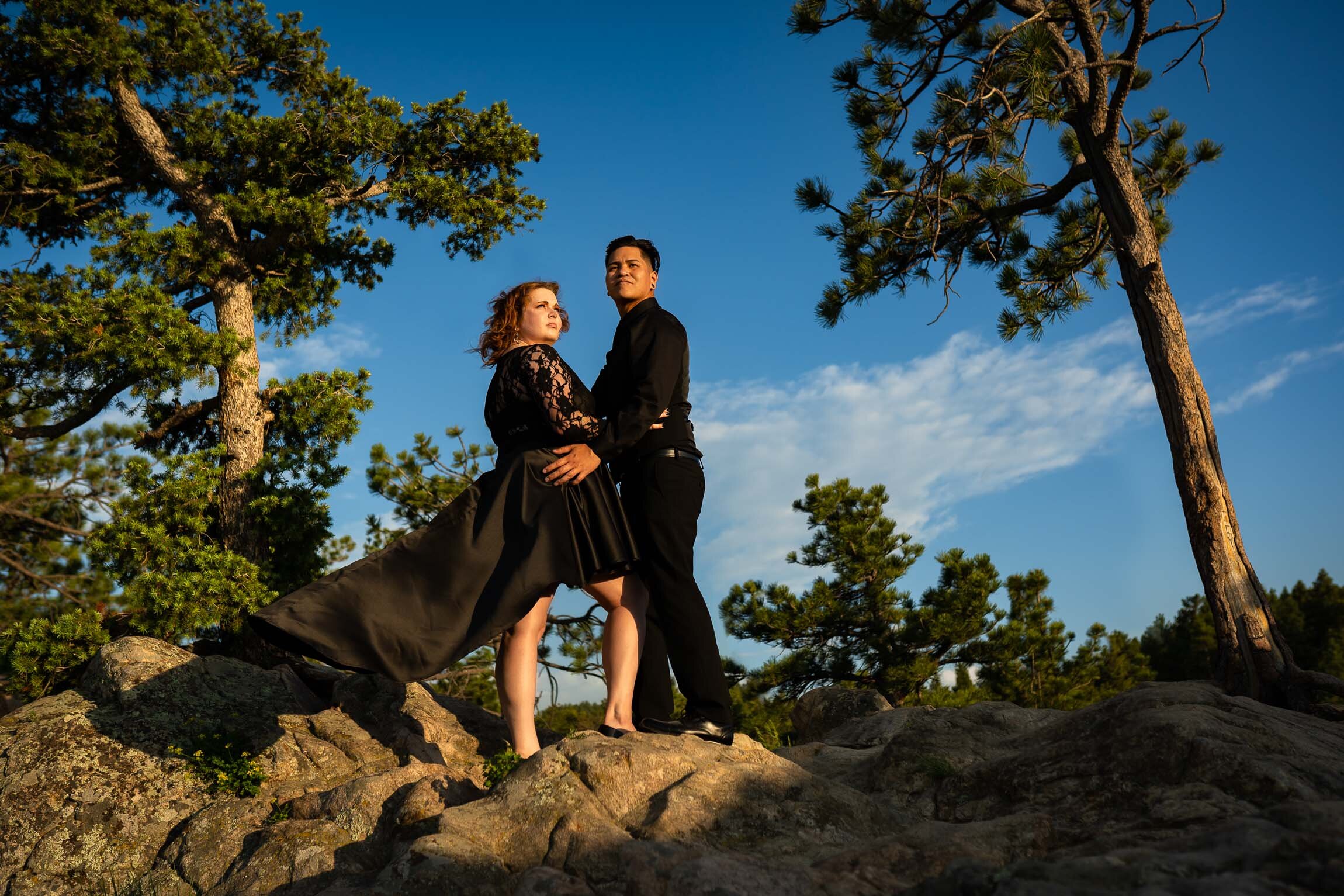 Engaged couple embraces for a portrait on a rocky ledge overlooking the mountains during golden hour, Engagement Session, Engagement Photos, Engagement Photos Inspiration, Engagement Photography, Engagement Photographer, Summer Engagement Photos, Mountain Engagement Photos, Lost Gulch Overlook engagement session, Lost Gulch Overlook engagement photos, Lost Gulch Overlook engagement photography, Lost Gulch Overlook engagement photographer, Lost Gulch Overlook  engagement inspiration, Boulder engagement session, Boulder engagement photos, Boulder engagement photography, Boulder engagement photographer, Boulder engagement inspiration, Colorado engagement session, Colorado engagement photos, Colorado engagement photography, Colorado engagement photographer, Colorado engagement inspiration