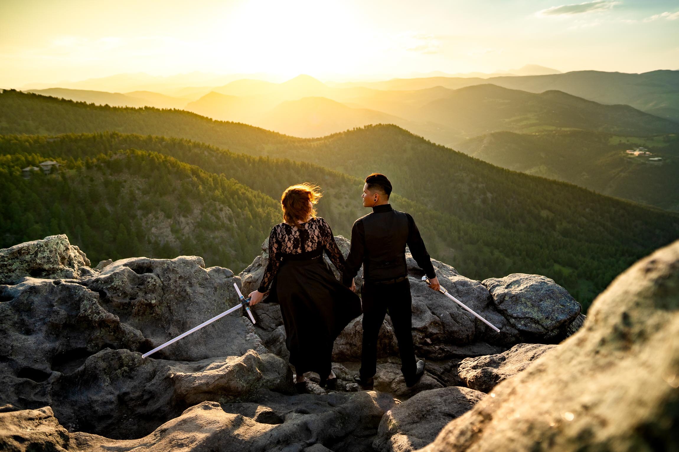 Engaged couple jumps into cosplay with their light sabers on a rocky ledge overlooking the mountains during golden hour, Engagement Session, Engagement Photos, Engagement Photos Inspiration, Engagement Photography, Engagement Photographer, Summer Engagement Photos, Mountain Engagement Photos, Lost Gulch Overlook engagement session, Lost Gulch Overlook engagement photos, Lost Gulch Overlook engagement photography, Lost Gulch Overlook engagement photographer, Lost Gulch Overlook  engagement inspiration, Boulder engagement session, Boulder engagement photos, Boulder engagement photography, Boulder engagement photographer, Boulder engagement inspiration, Colorado engagement session, Colorado engagement photos, Colorado engagement photography, Colorado engagement photographer, Colorado engagement inspiration